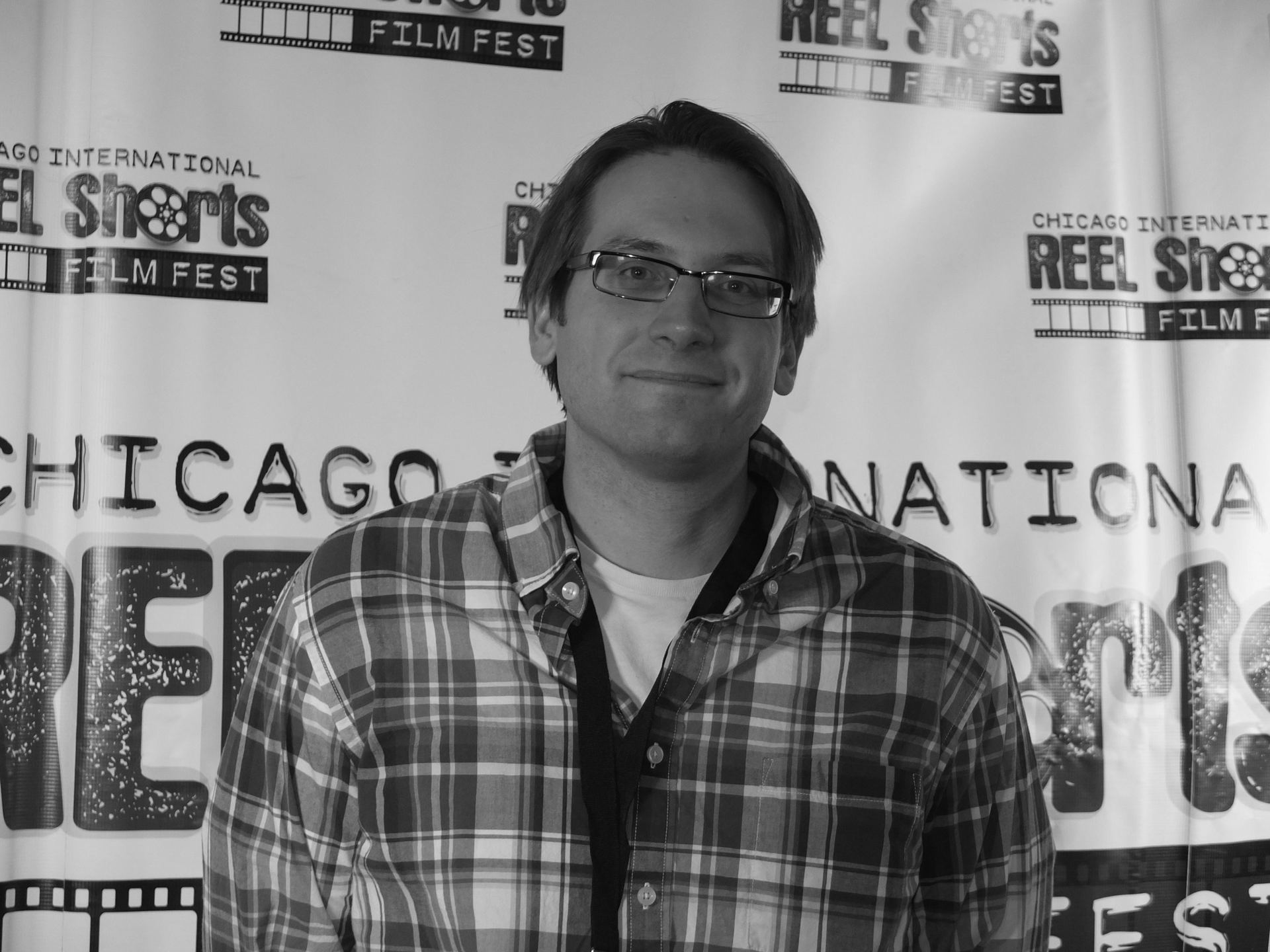 Man in glasses smiles in front of a 