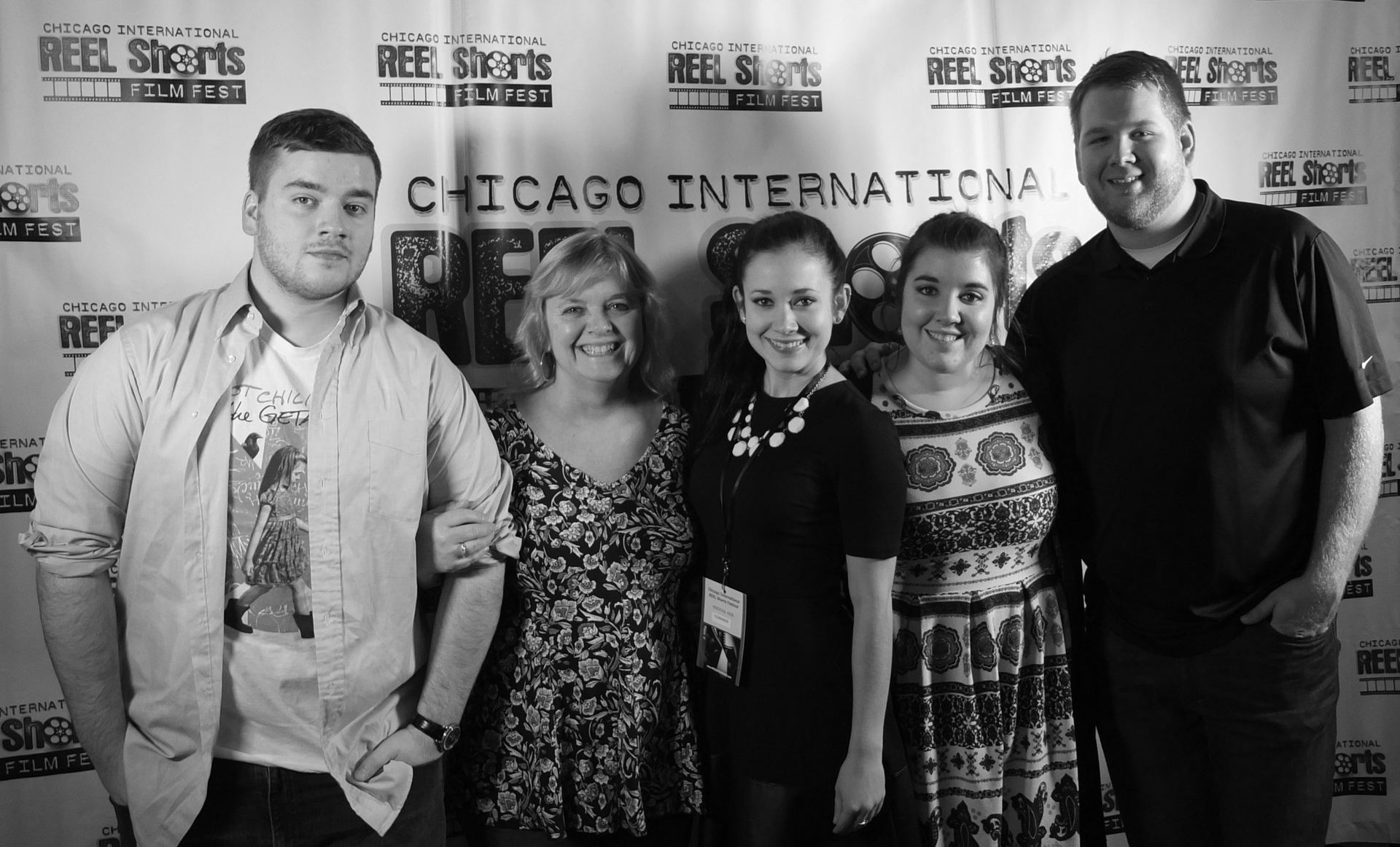 Five people posing in front of a Chicago International Reel Shorts backdrop; smiling and looking at the camera.