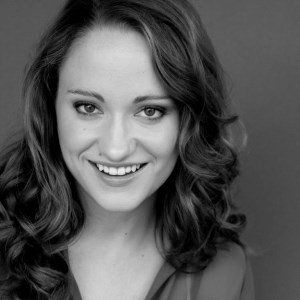A woman with long hair is smiling in a black and white photo.