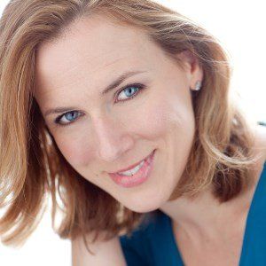 A woman with brown hair and blue eyes is smiling for the camera.
