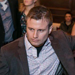 A man in a suit and tie is sitting in front of a group of people.