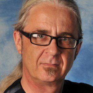 A man with glasses and a ponytail looks at the camera