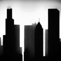 Silhouetted cityscape against a bright sky; various skyscraper shapes in black.