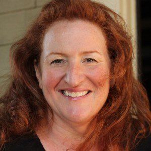 A woman with red hair is smiling for the camera.