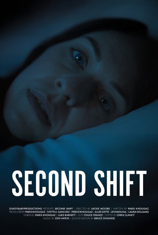 Woman in bed, looking uneasy, blue-toned. 