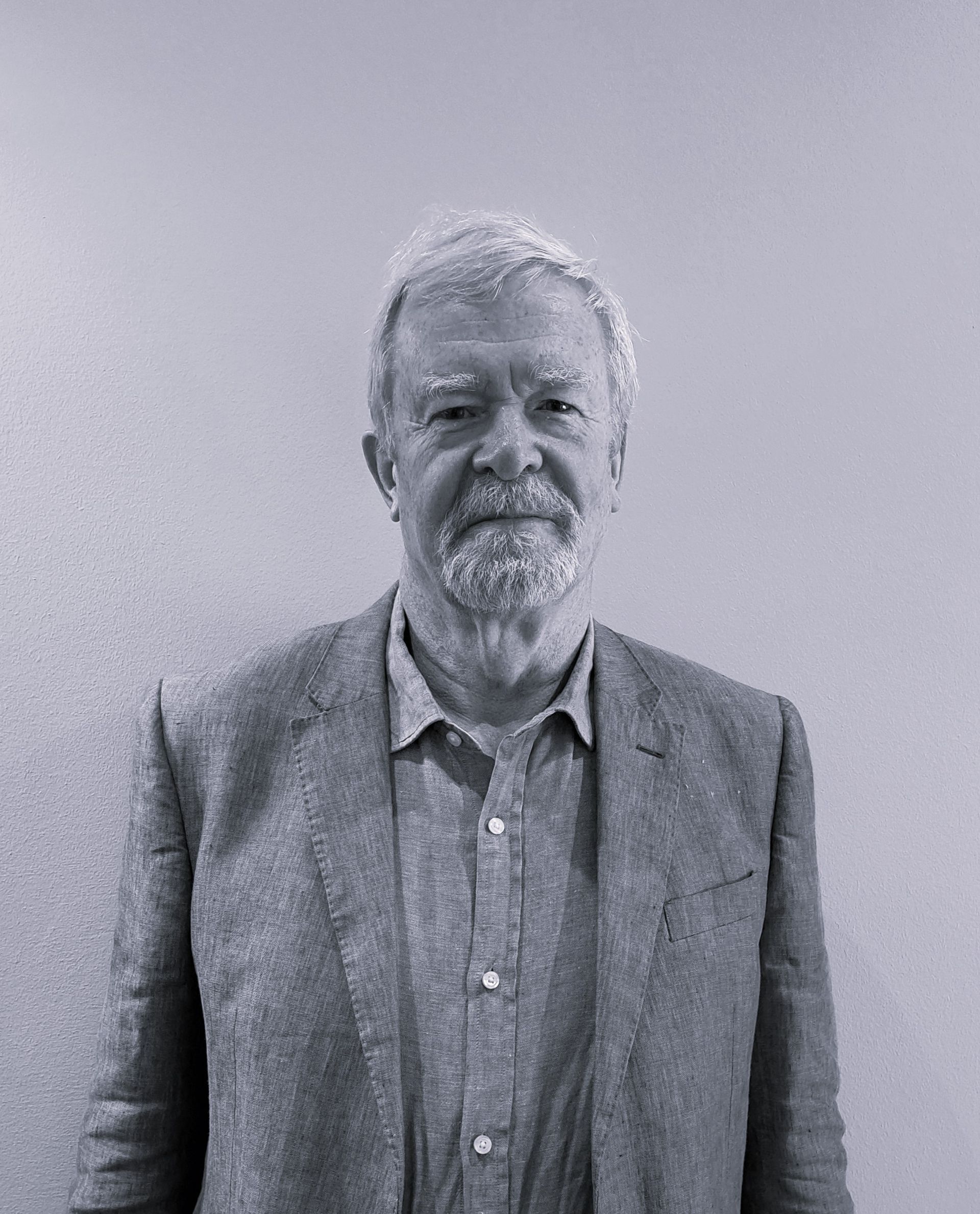 Quastel Associates, Valuers | A man with a beard is wearing a suit and standing in front of a wall.