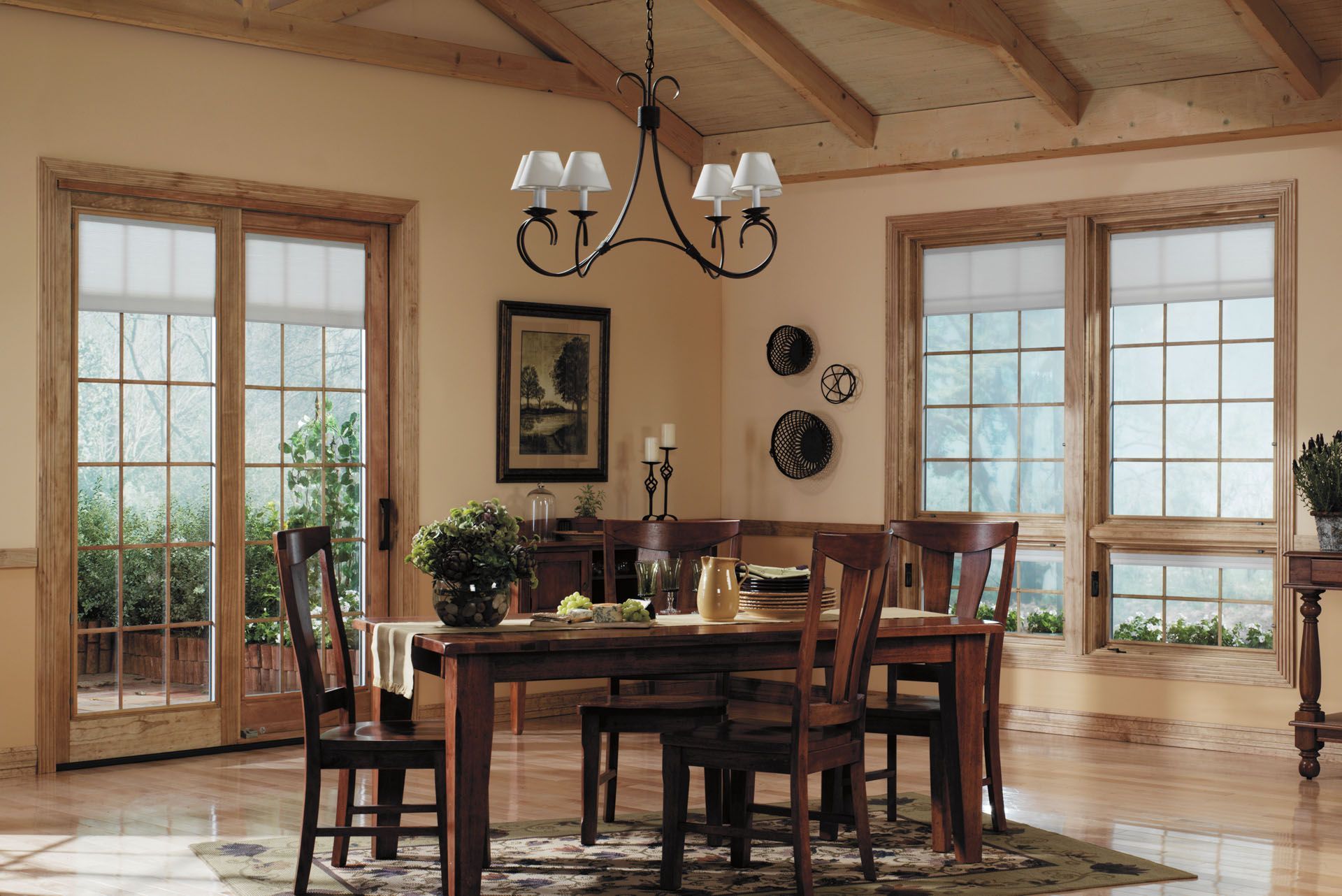 Dining room with wooden table, chairs, windows, and a chandelier.