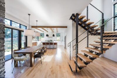 Modern home interior with hardwood floors, open staircase, dining area, and kitchen.