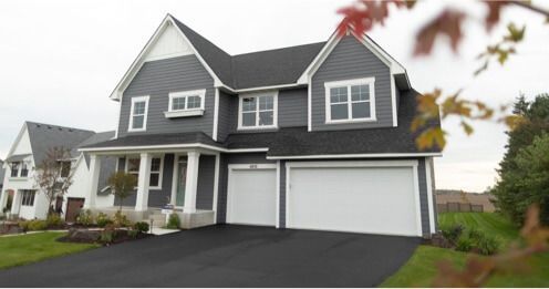Gray two-story house with white trim and garage, set on a green lawn.