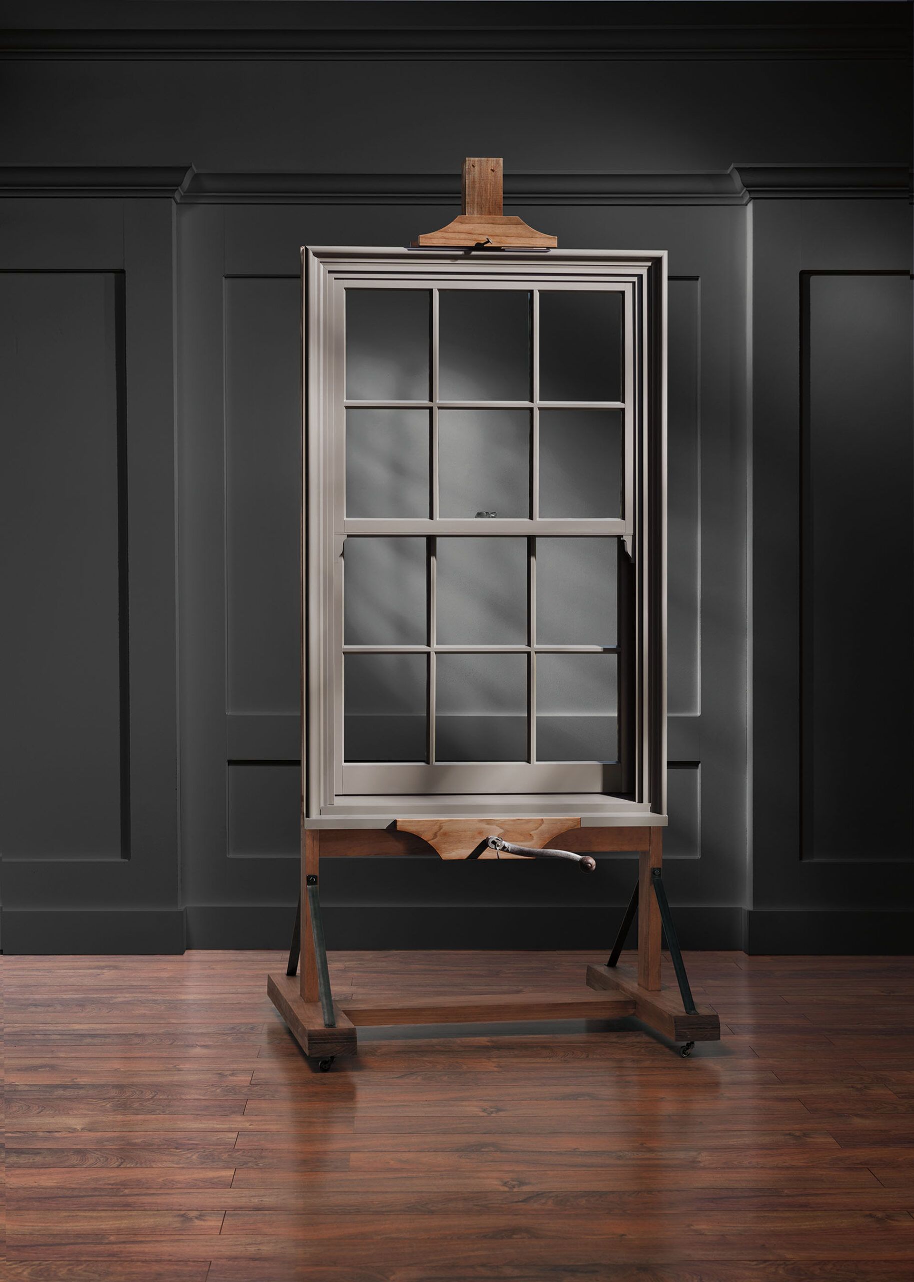Wooden window frame on an easel against a dark wall and wood floor.
