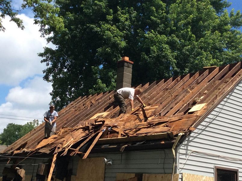 a couple of men working on a roof.
