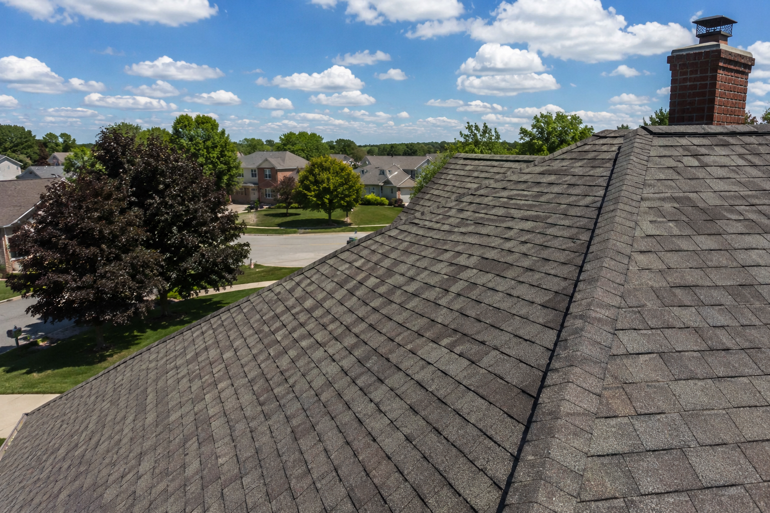 “High-angle view of a residential asphalt shingle roof during a bright Michigan summer day