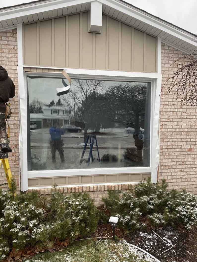 a man standing on a ladder next to a window.