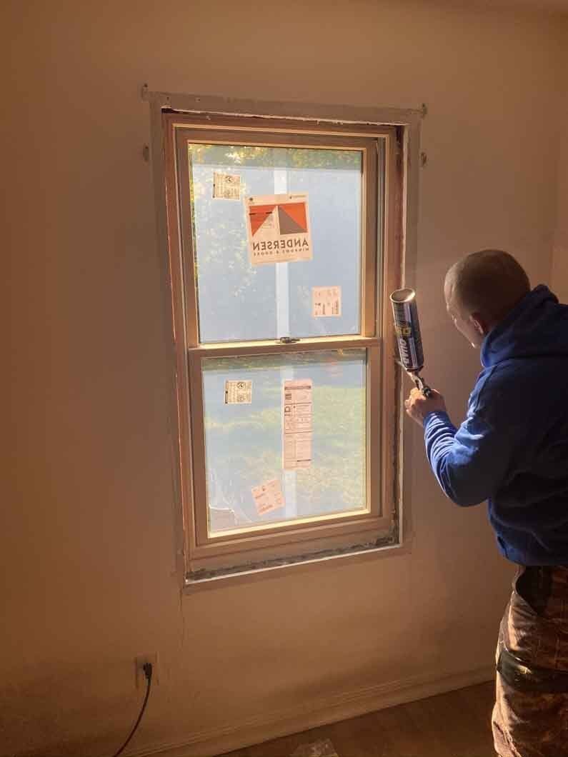 a man using a spray can to paint a window.
