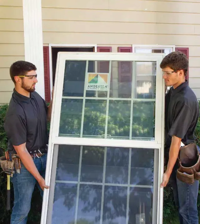 Two men in black clothing carefully move a glass door