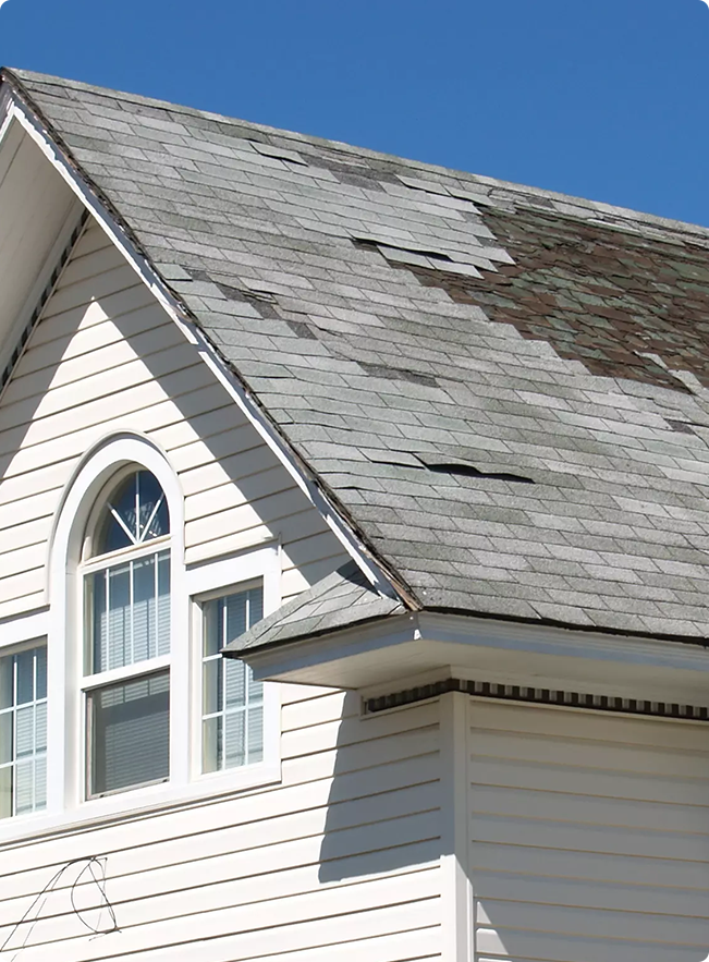 A white house with visible storm damage on rooftop