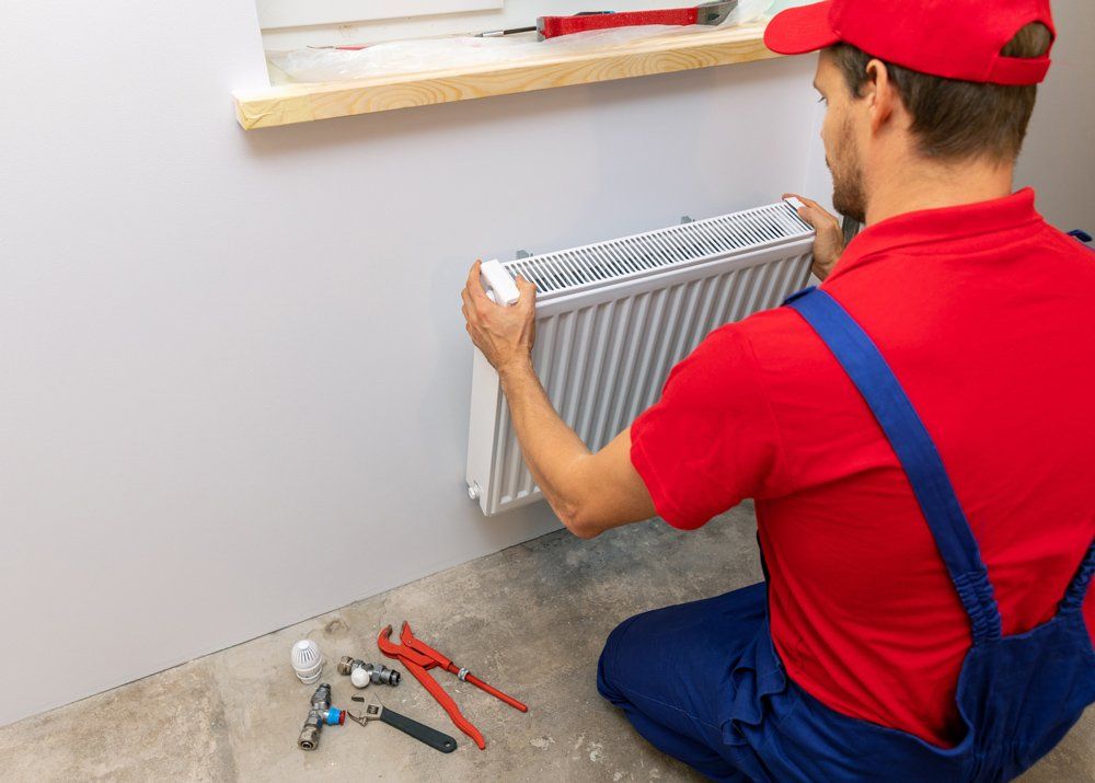 Plumber Installing Heating Radiator — Irwin, PA — Westmoreland Affordable Plumbing Heating & Cooling