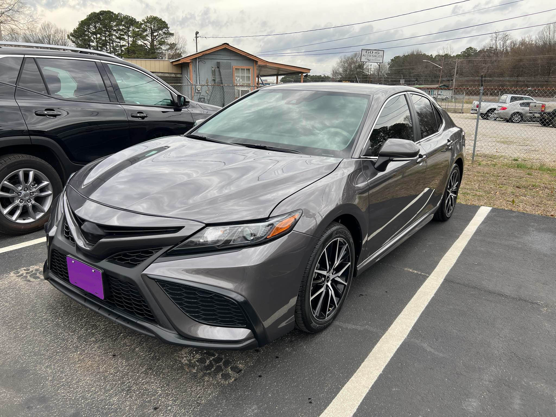 A gray toyota camry is parked in a parking lot next to a black suv.  | Windham Bodyshop