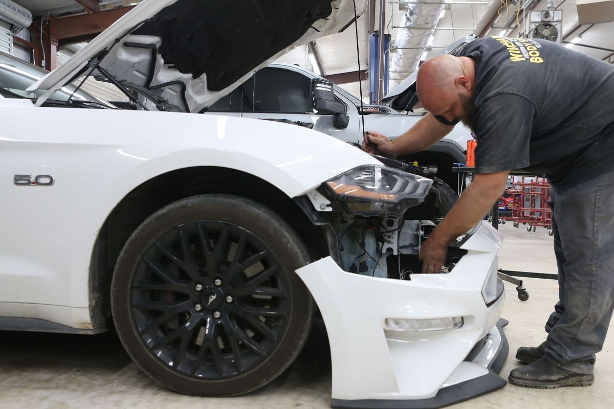 Our expert staff repairing a white car's front | Windham Bodyshop