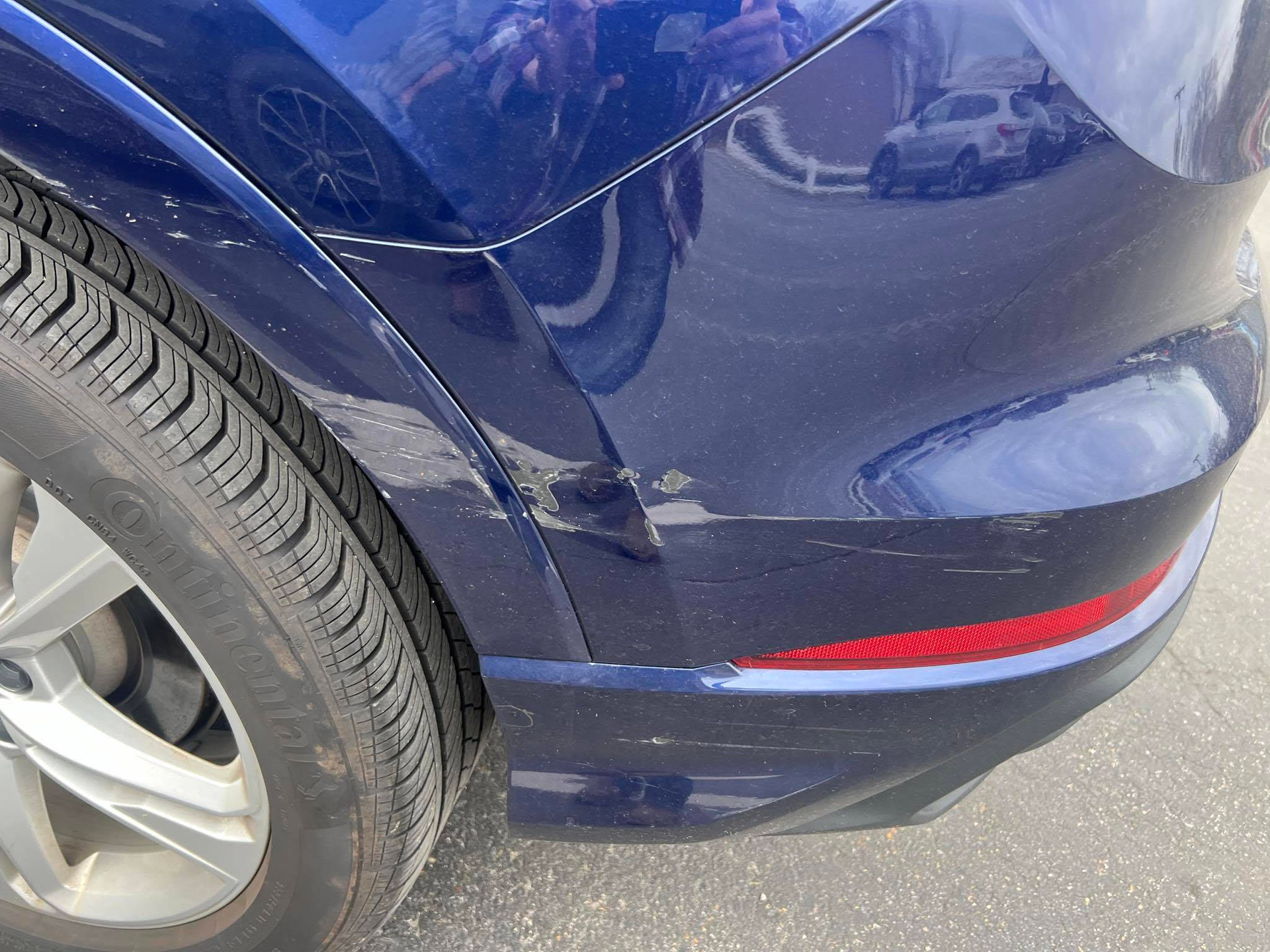 A blue car with a damaged bumper is parked on the side of the road.  | Windham Bodyshop