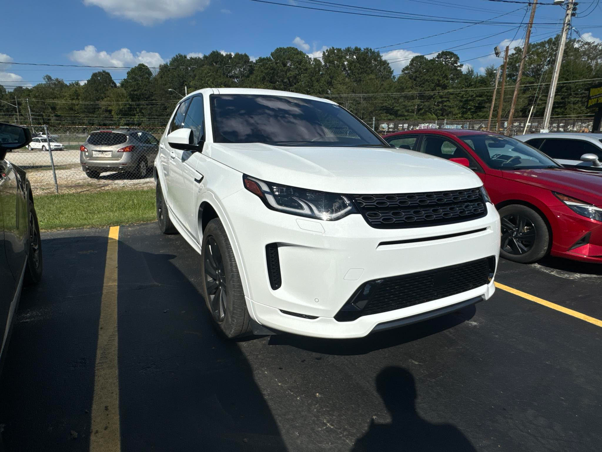 A white land rover discovery sport is parked in a parking lot.  | Windham Bodyshop