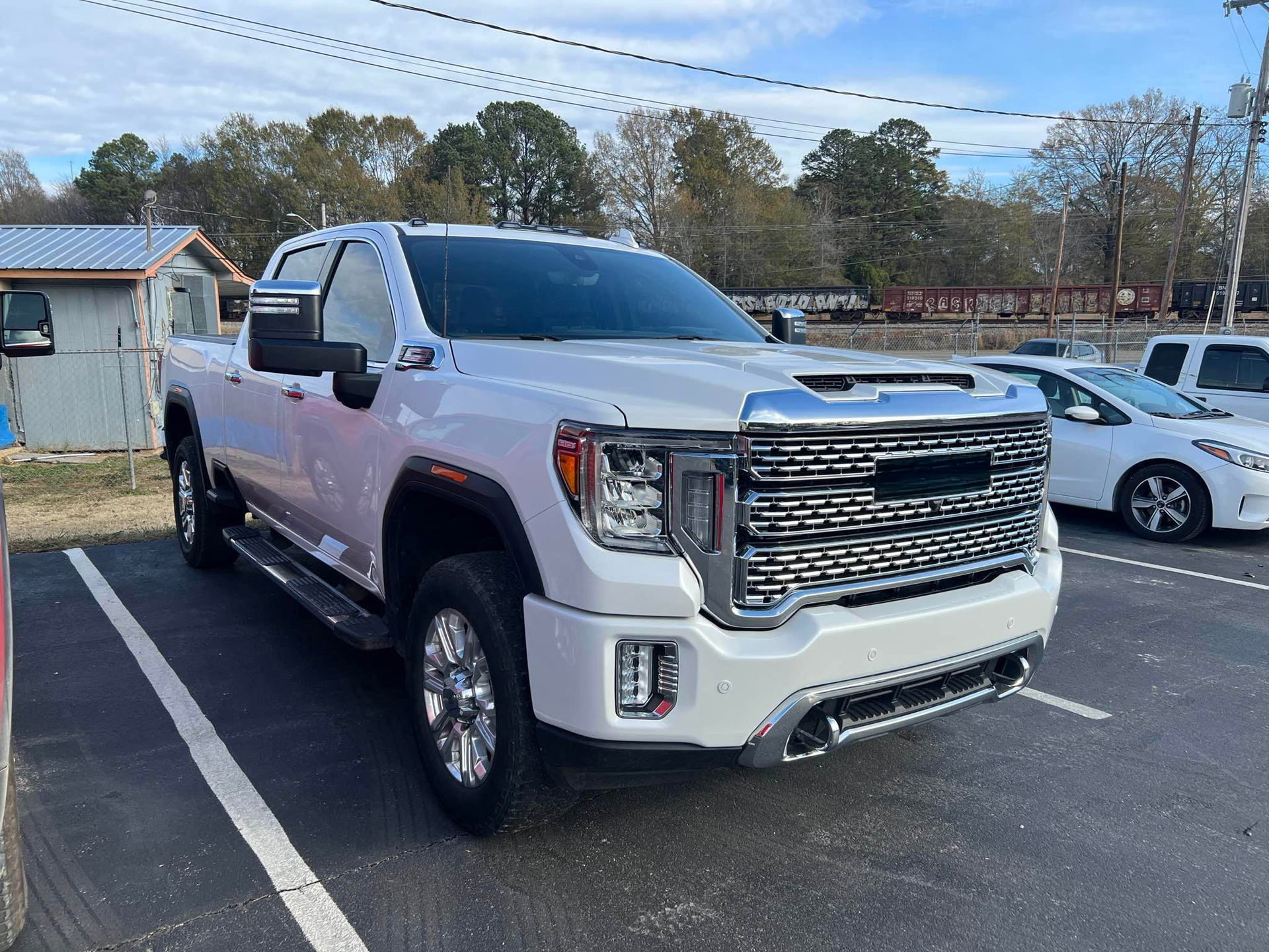 A white truck is parked in a parking lot next to a white car.  | Windham Bodyshop