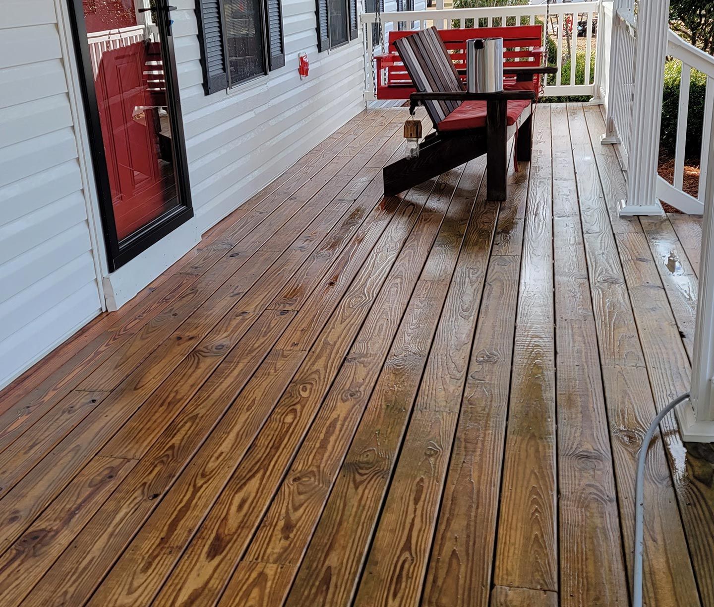 A wooden deck with a bench and chairs on it