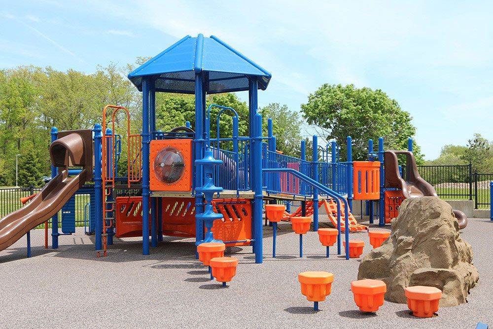 A large colorful playground in a park with trees in the background.