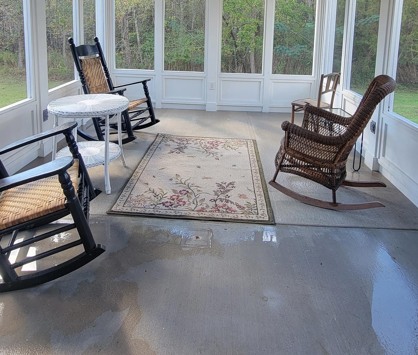 A screened in porch with rocking chairs and a table