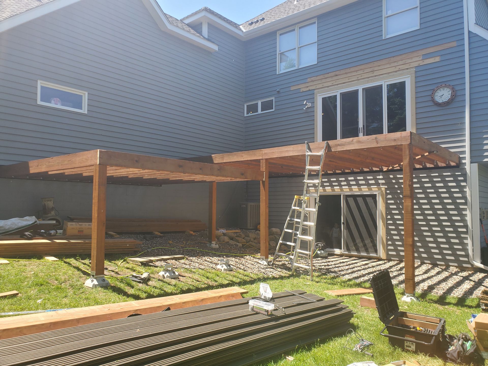 A wooden deck is being built in the backyard of a house.