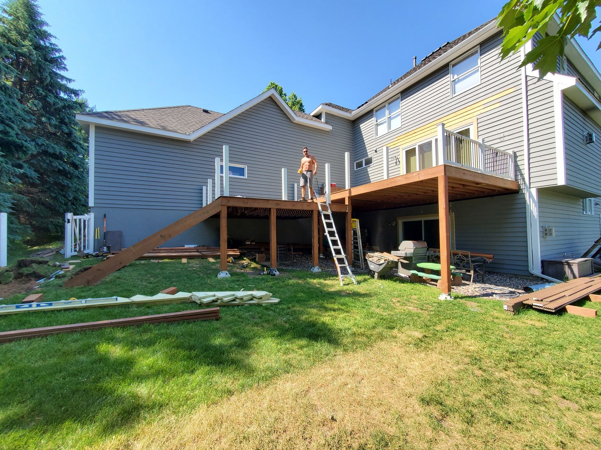 A man is standing on a wooden deck in front of a house.