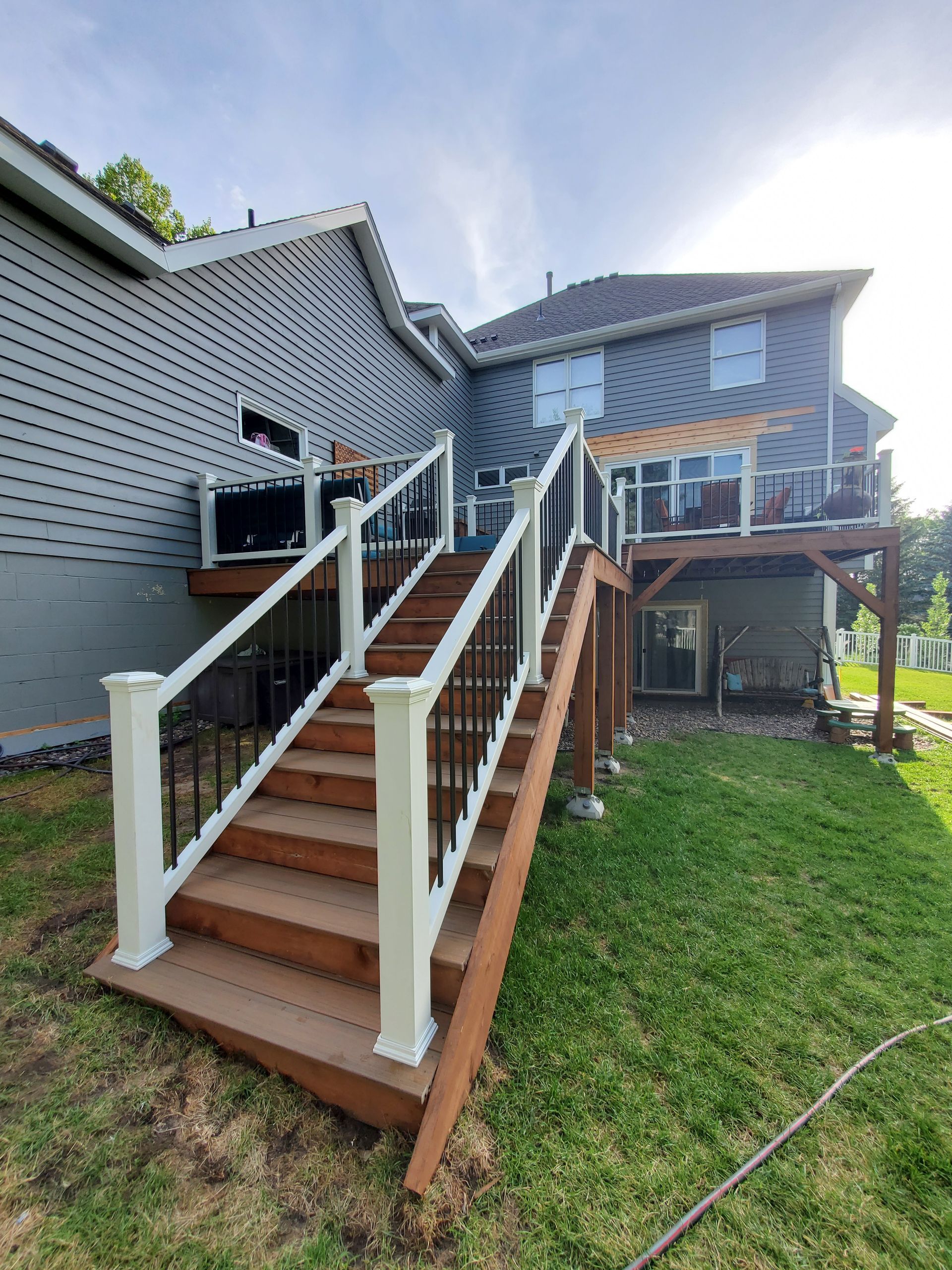 A wooden deck with stairs leading up to it and a house in the background.