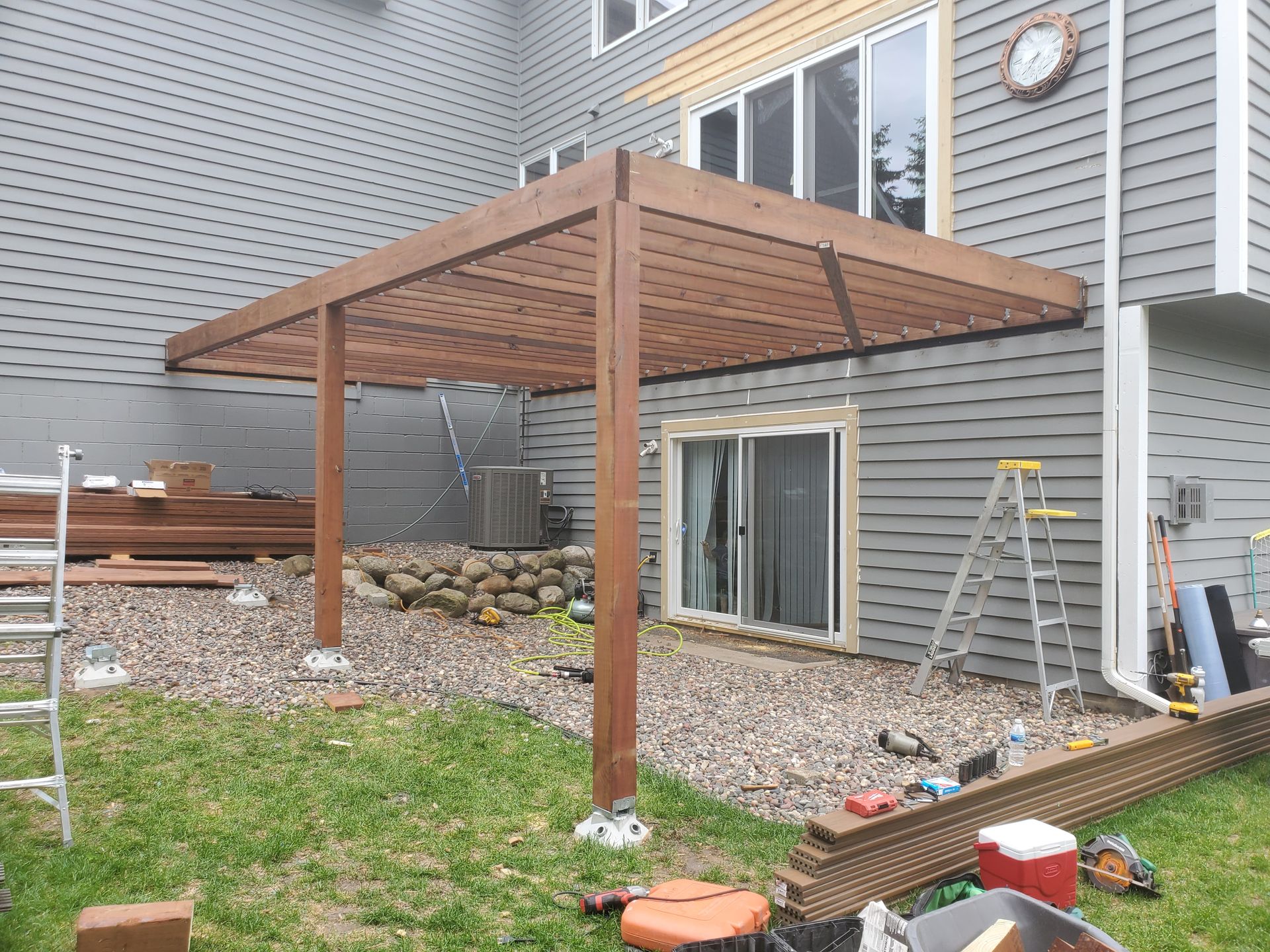A wooden pergola is being built in the backyard of a house.