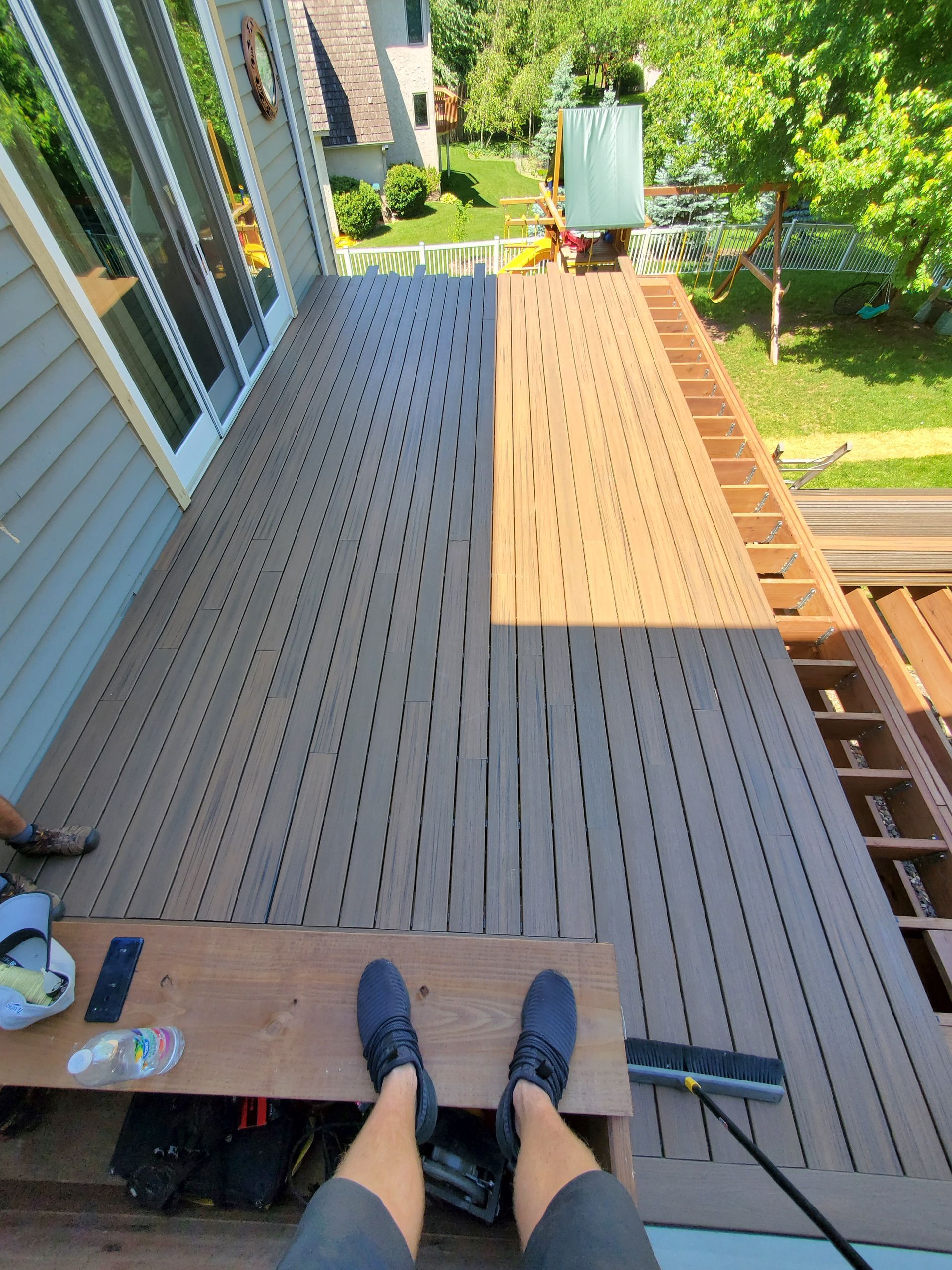 A person 's feet are sitting on a wooden deck