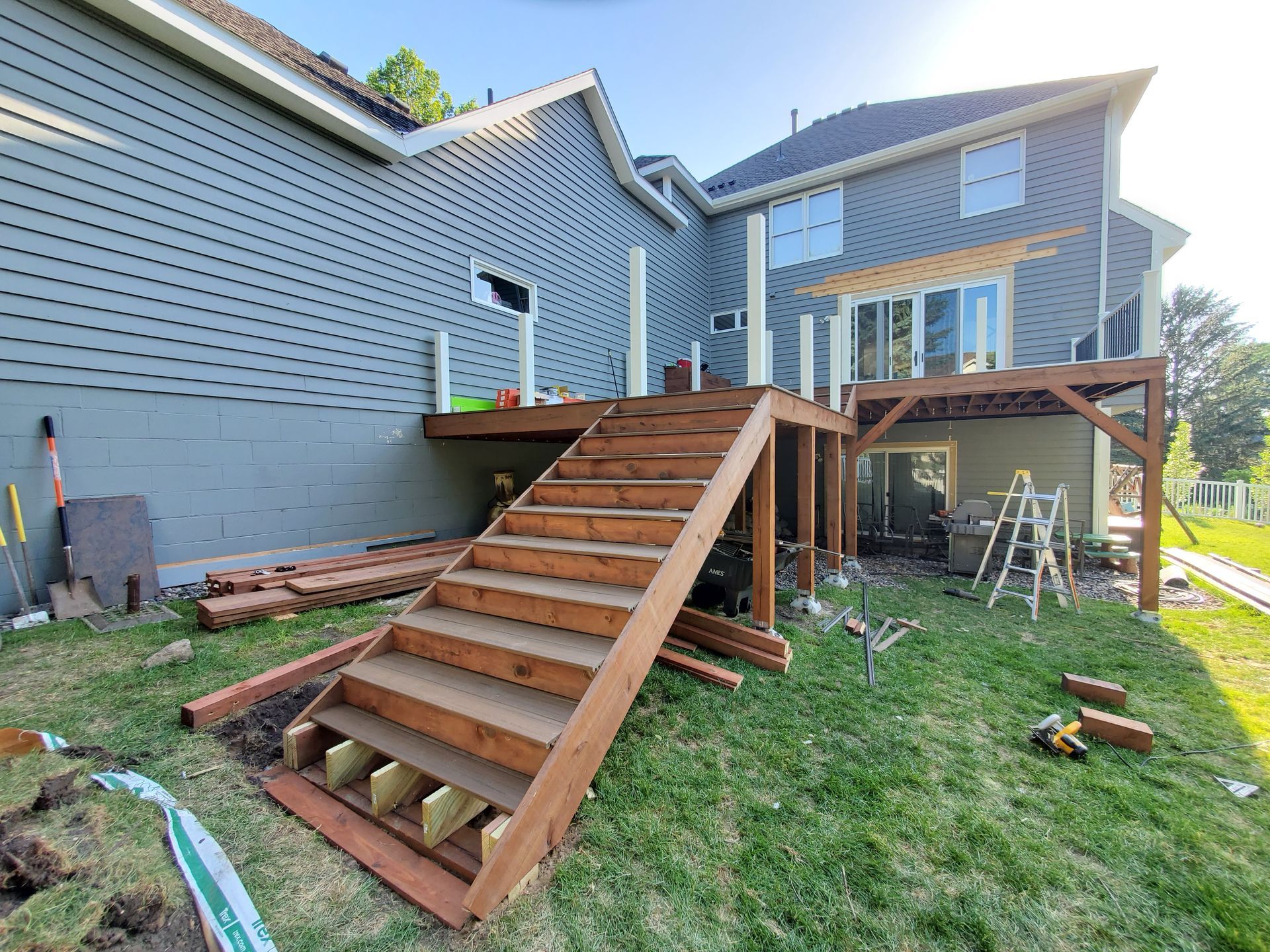 A wooden deck is being built in the backyard of a house.