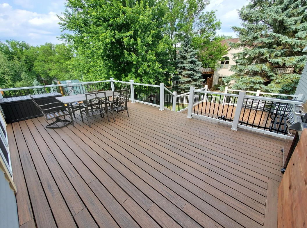 A large wooden deck with a table and chairs on it.