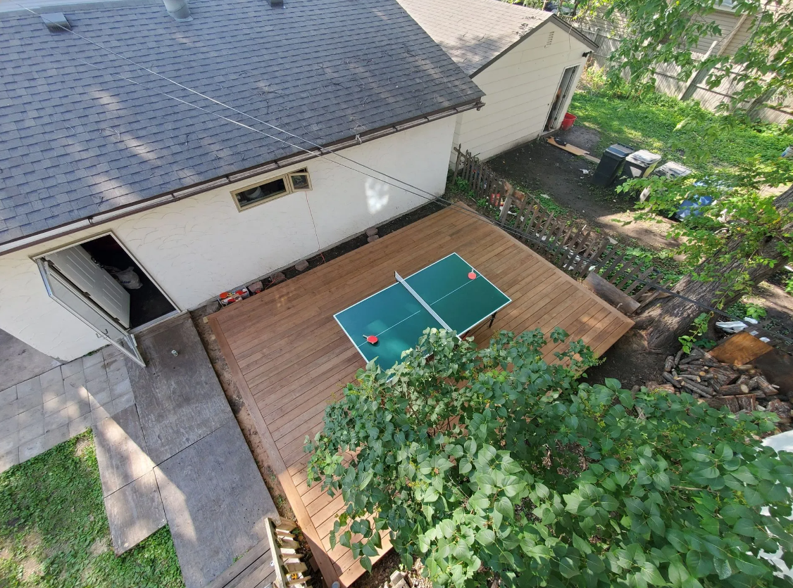 An aerial view of a wooden deck with a ping pong table on it.