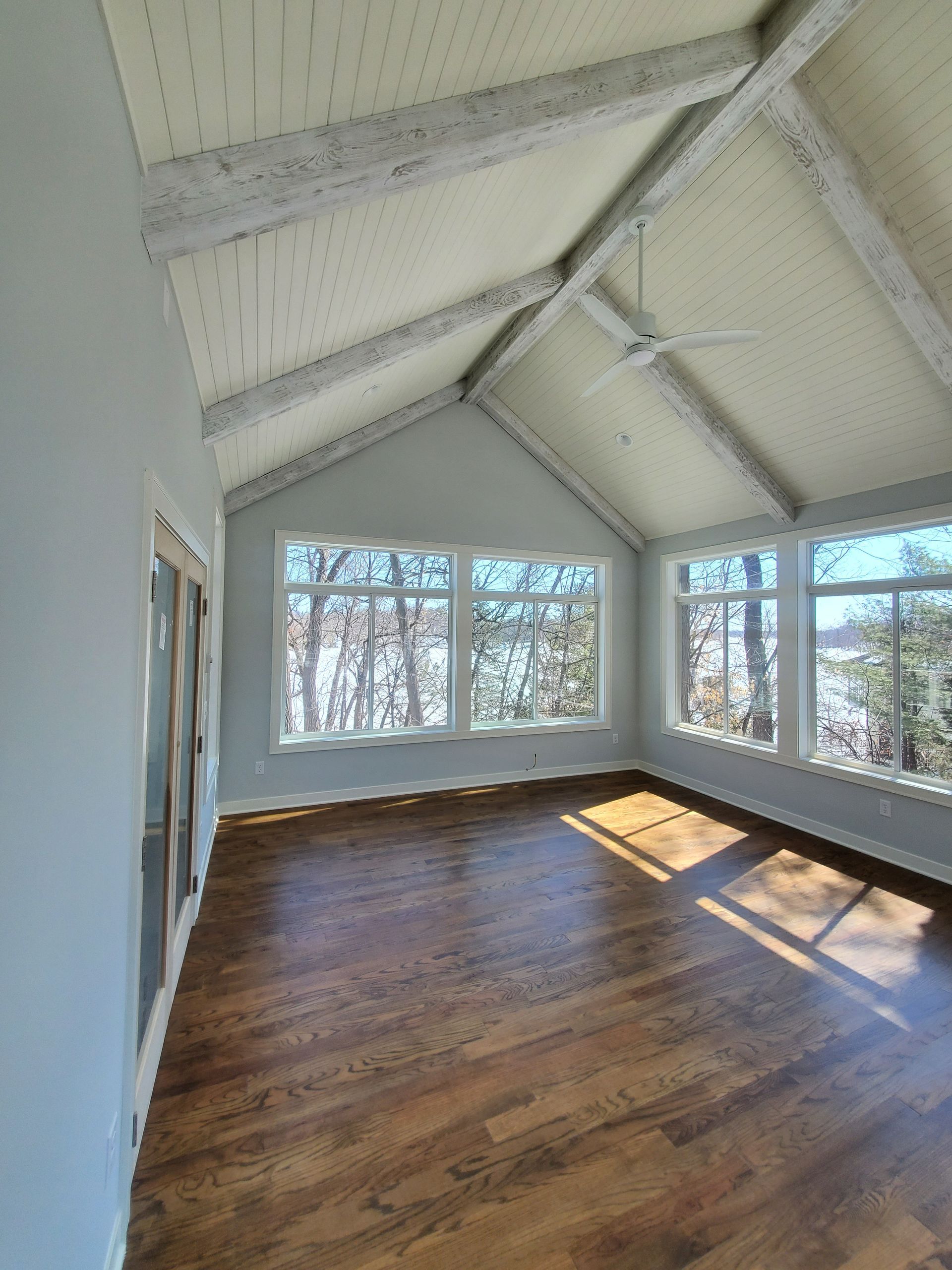 A large empty room with hardwood floors and a vaulted ceiling.