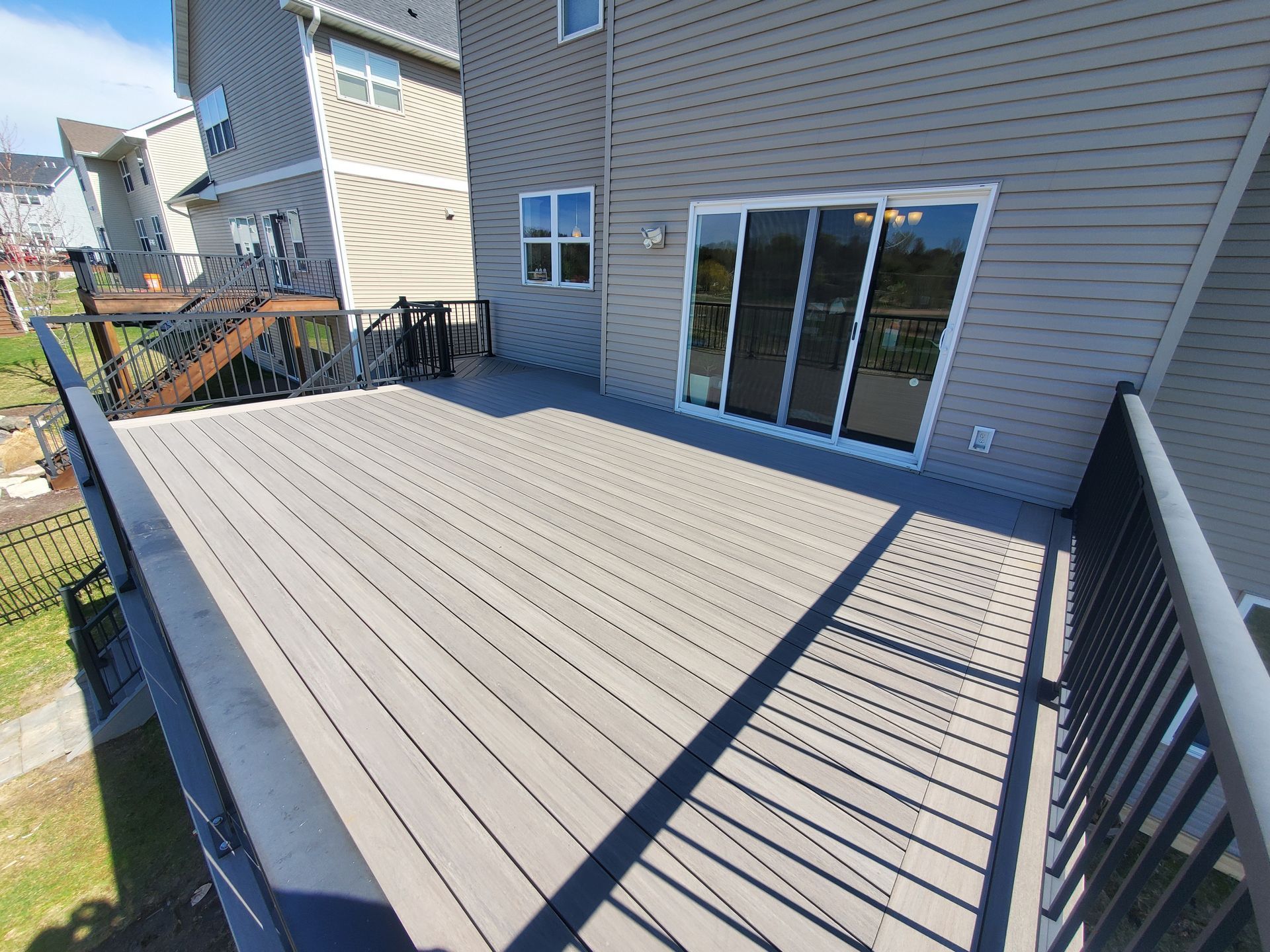 A large deck with a sliding glass door in the backyard of a house.