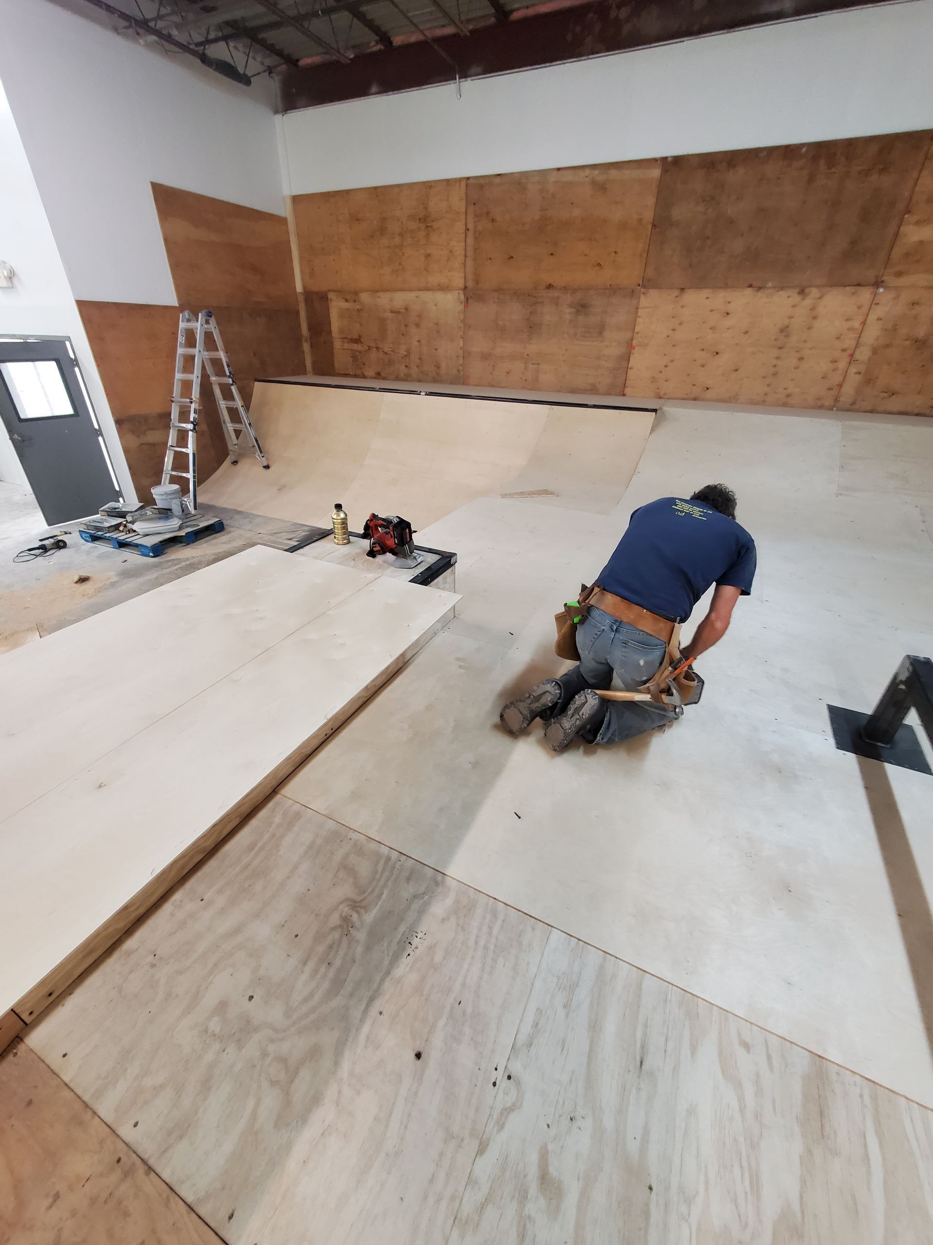 A man is kneeling on a wooden floor in a room