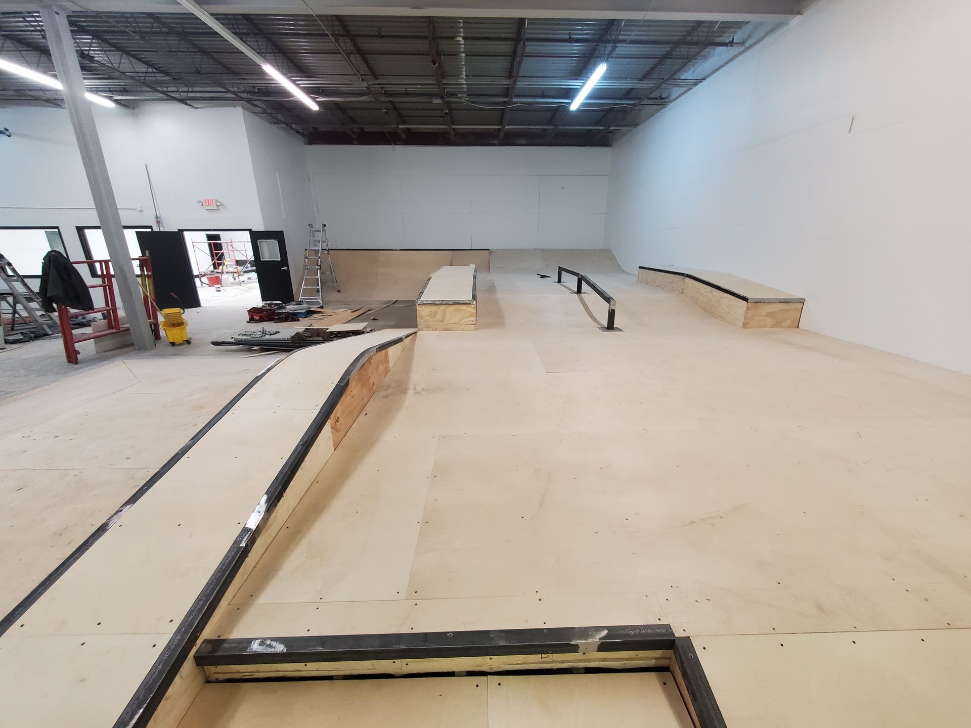 A skateboard park is being built in a large warehouse.