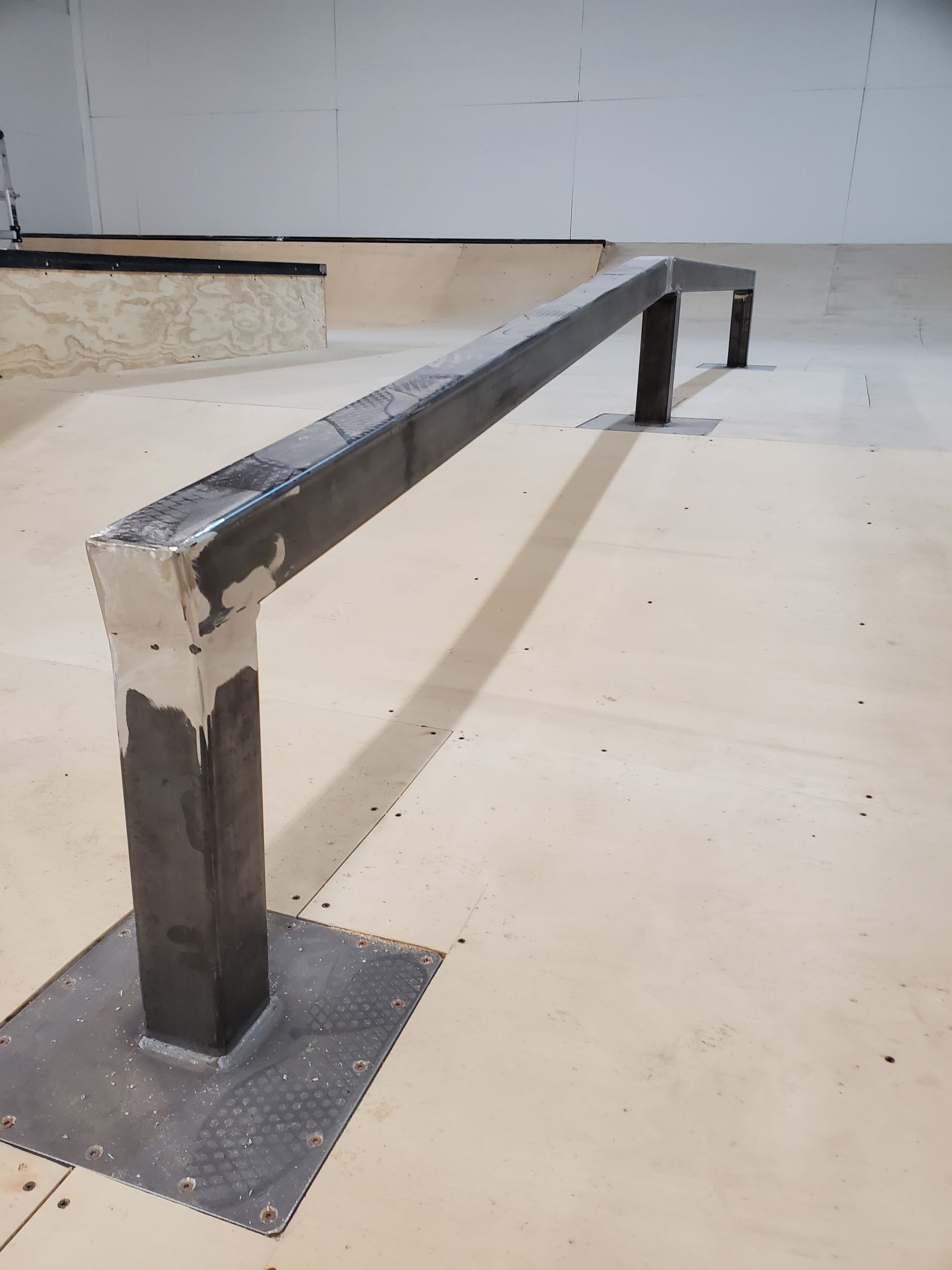 A metal railing is in the middle of a skate park