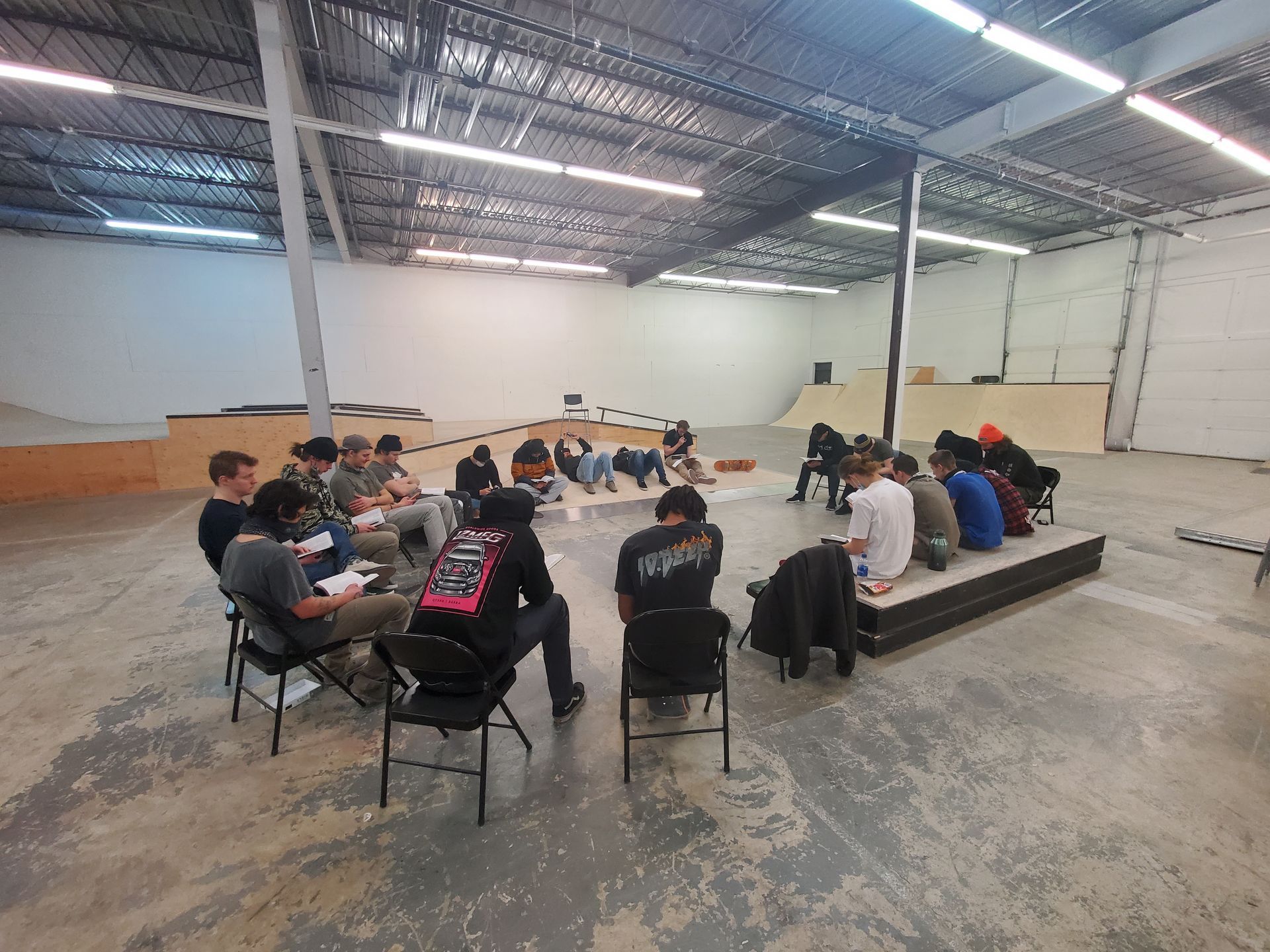A group of people are sitting in a circle in a warehouse.