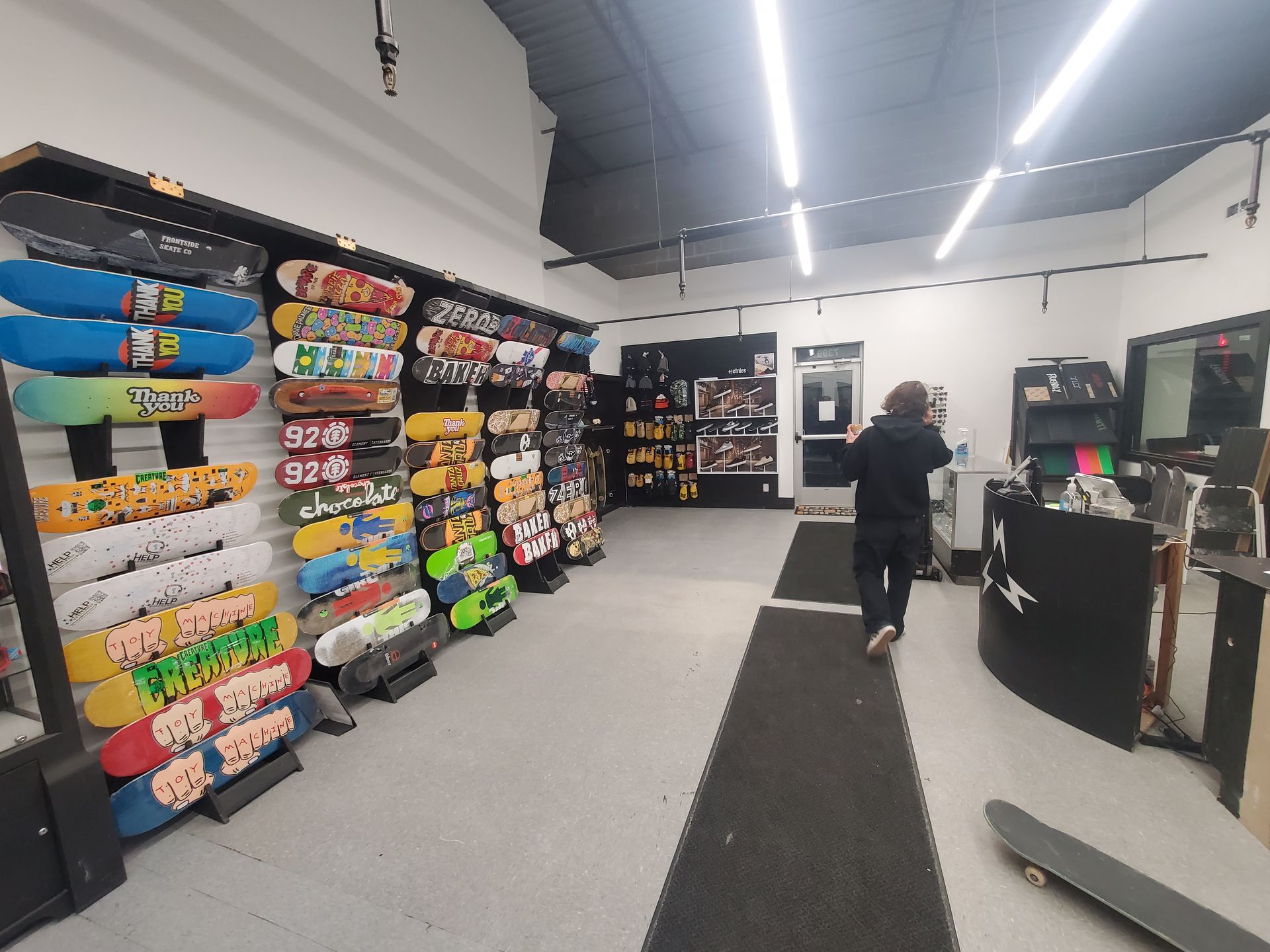 A man is walking through a store filled with skateboards.