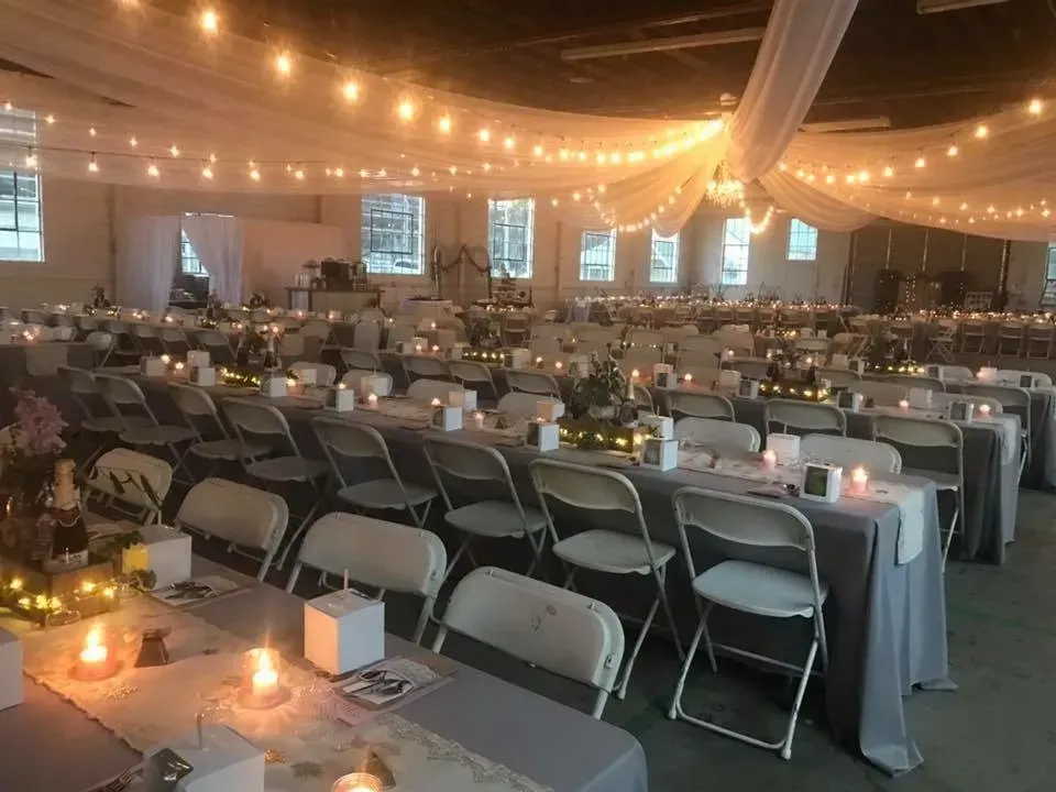 Large event space, tables set for a gathering, decorated with lights and candles.