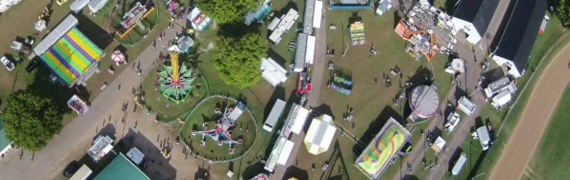 Aerial view of a carnival with rides, tents, and people.