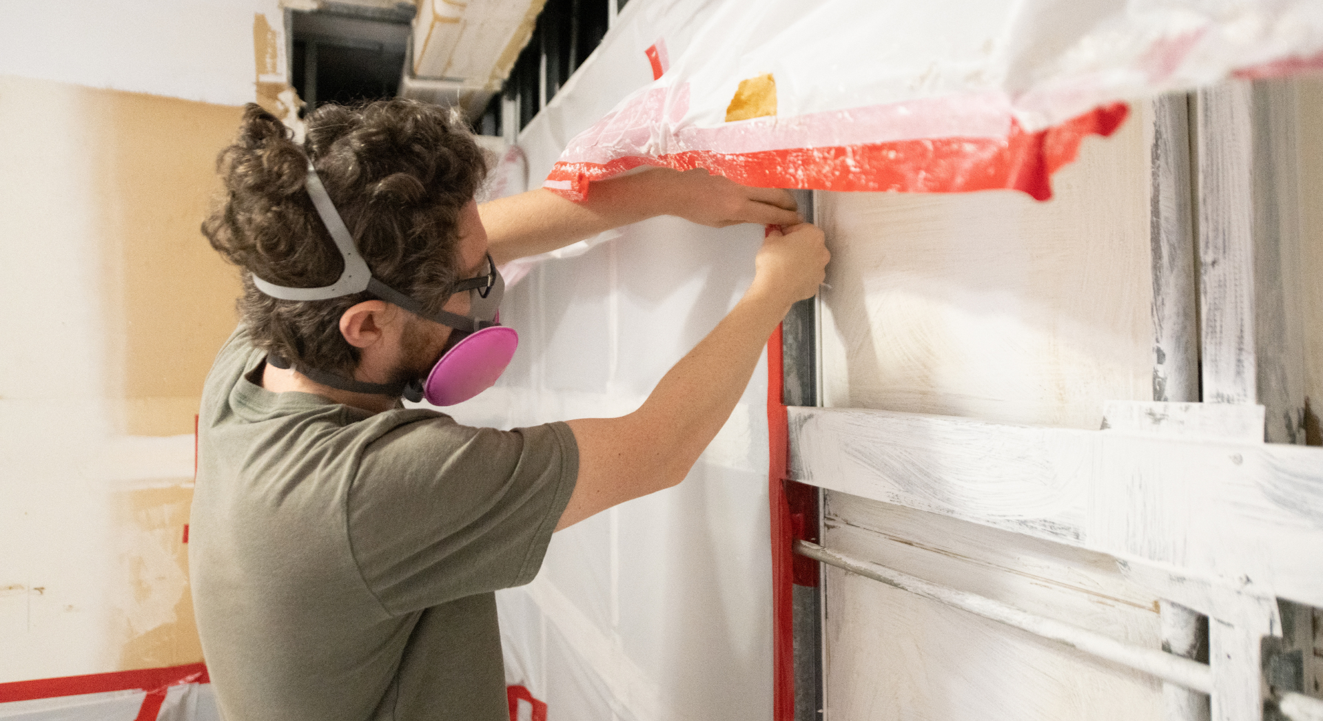 A man wearing a mask is working on a wall.