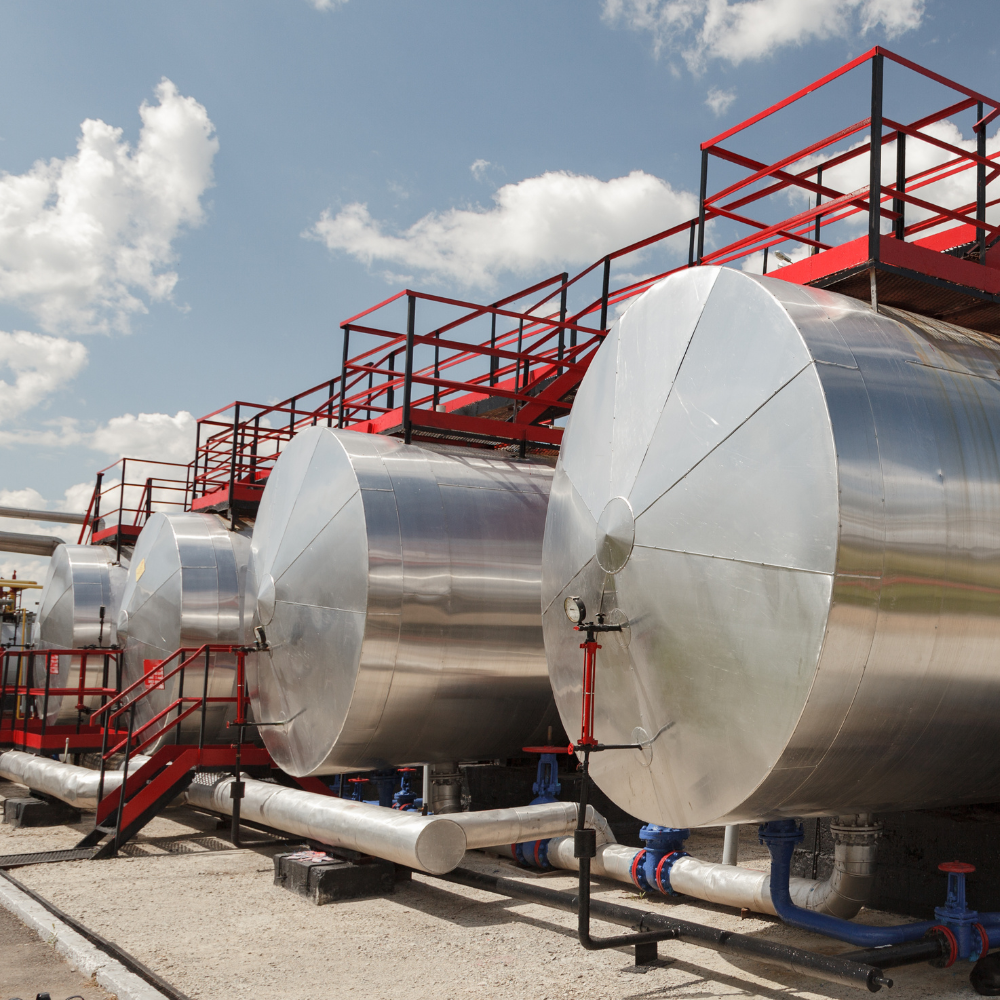 A row of large metal petroleum tanks with stairs leading up to them for an industrial petrol system installed by Hampton Construction & Development