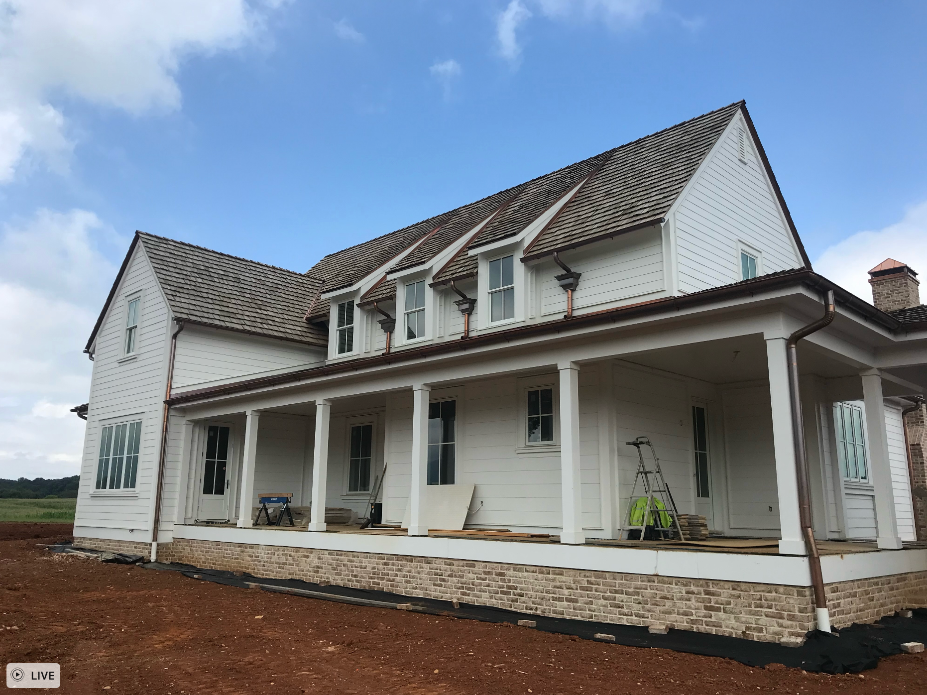 A large white house with a porch and a blue sky in the background