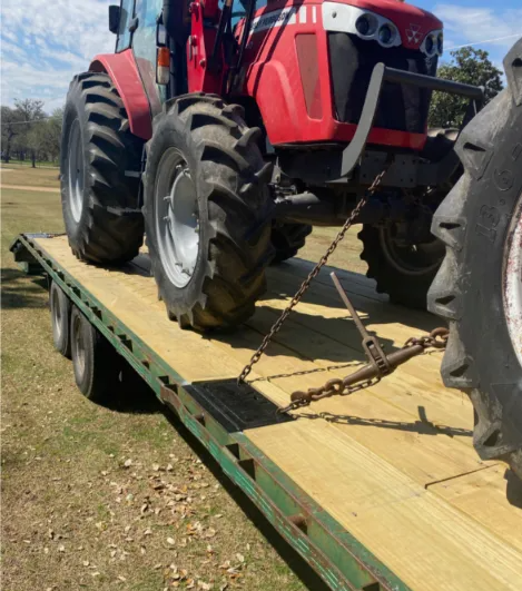 A close-up of a metal chain and padlock secured to an orange industrial structure against a dark, wooden background.